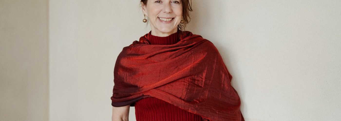 Gabriella Rist, in ein rotes Tuch gehüllt, lachend.