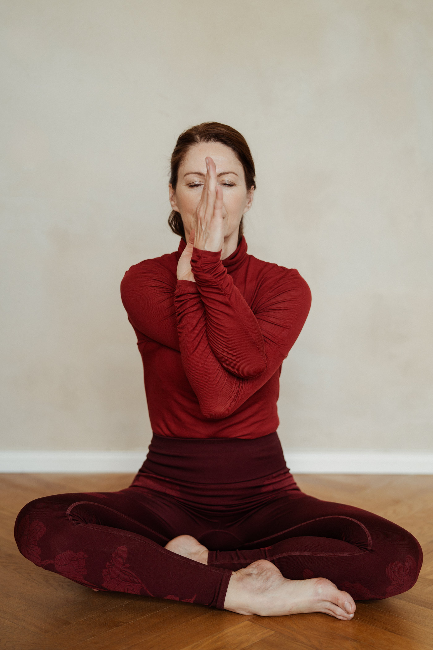 Gabriella Rist im Schneidersitz, die Arme vor dem Gesicht verschränkt – eine somatische Übung aus dem traumasensiblen Yoga, um das Nervensystem zu regulieren.